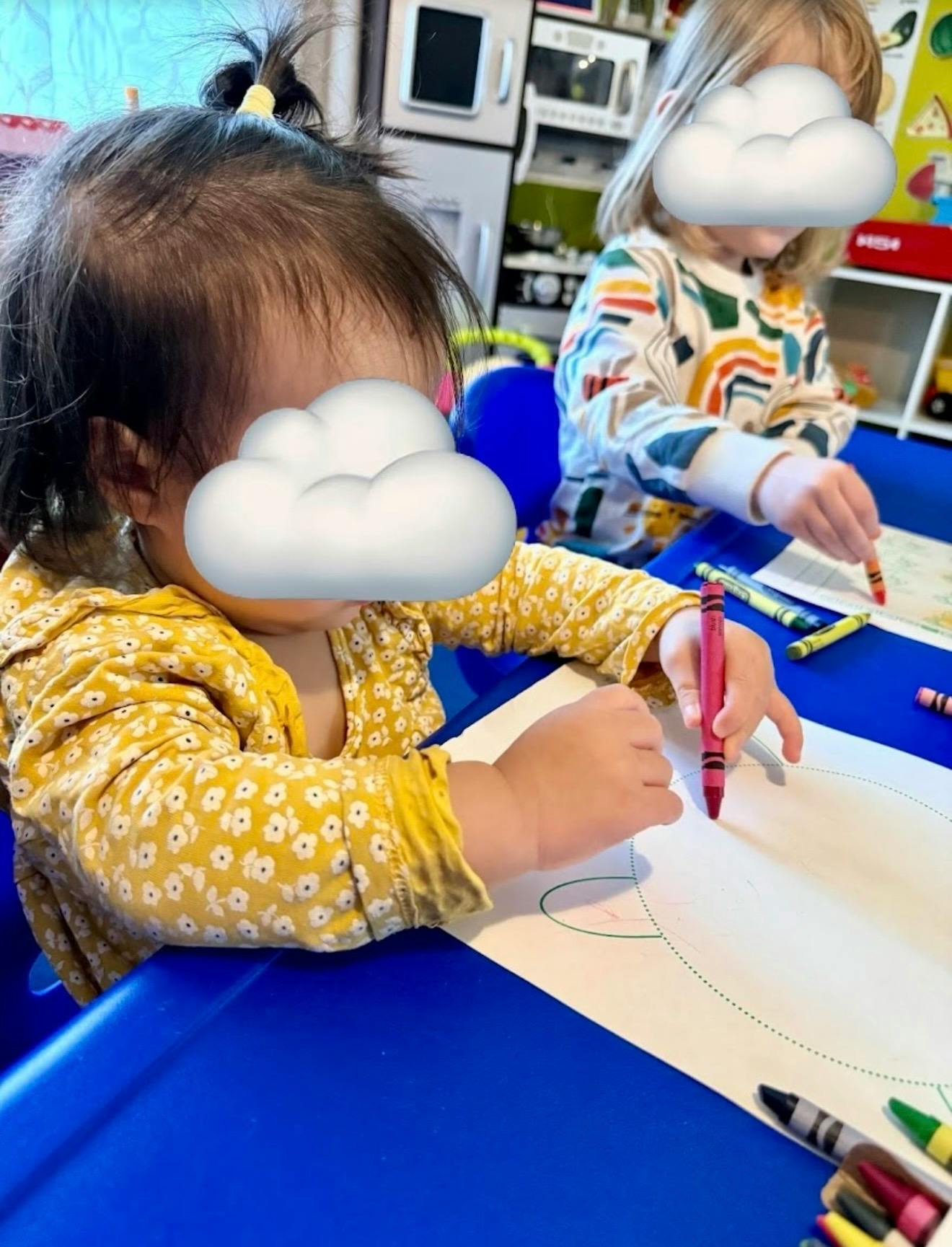 Two children coloring at a blue table