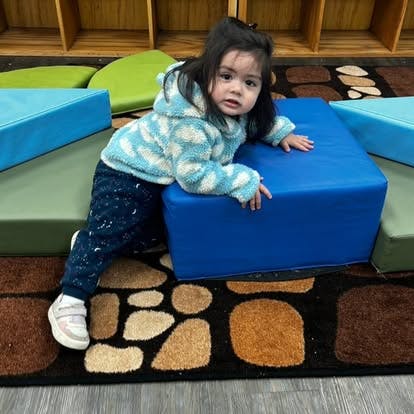 Child leaning on a blue soft play block