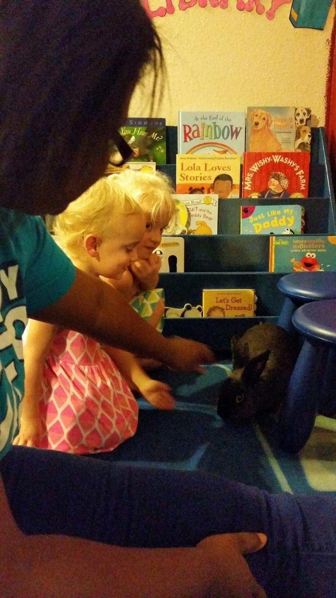 Person and two children interacting with a small animal