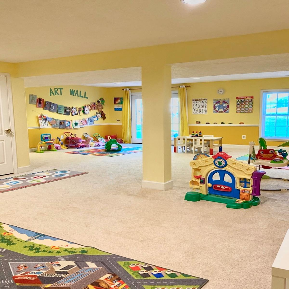 Playroom with toys, play mats, and an "Art Wall" sign