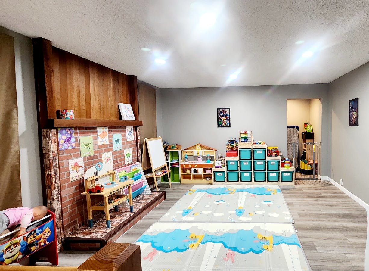 Playroom with a faux brick fireplace, toy storage, and play mats