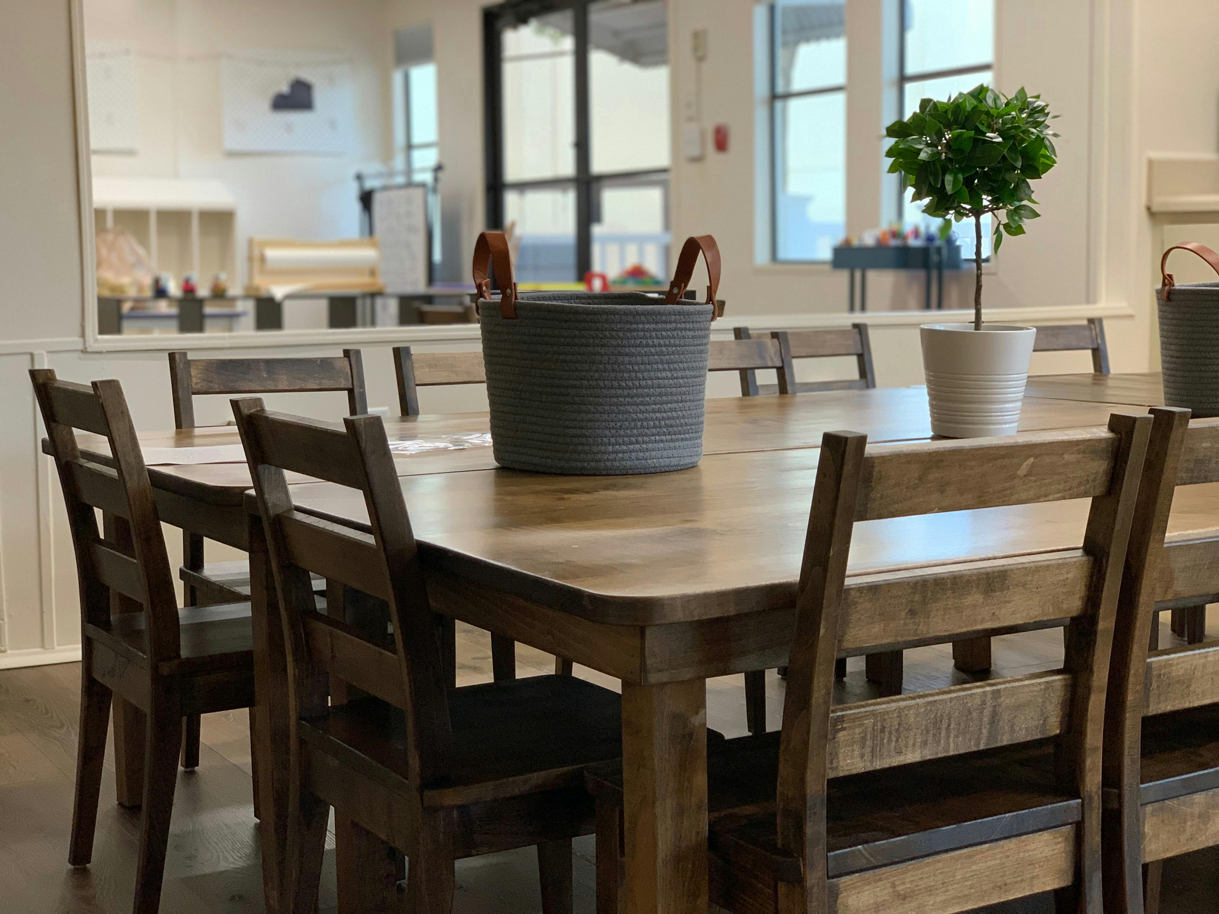 Wooden table with chairs, a gray basket, and a potted plant