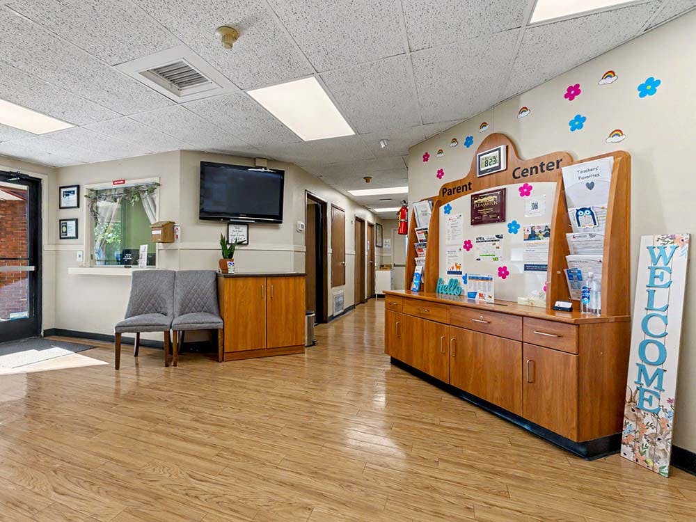 Foyer of a parent center with a reception window, seating, and information board