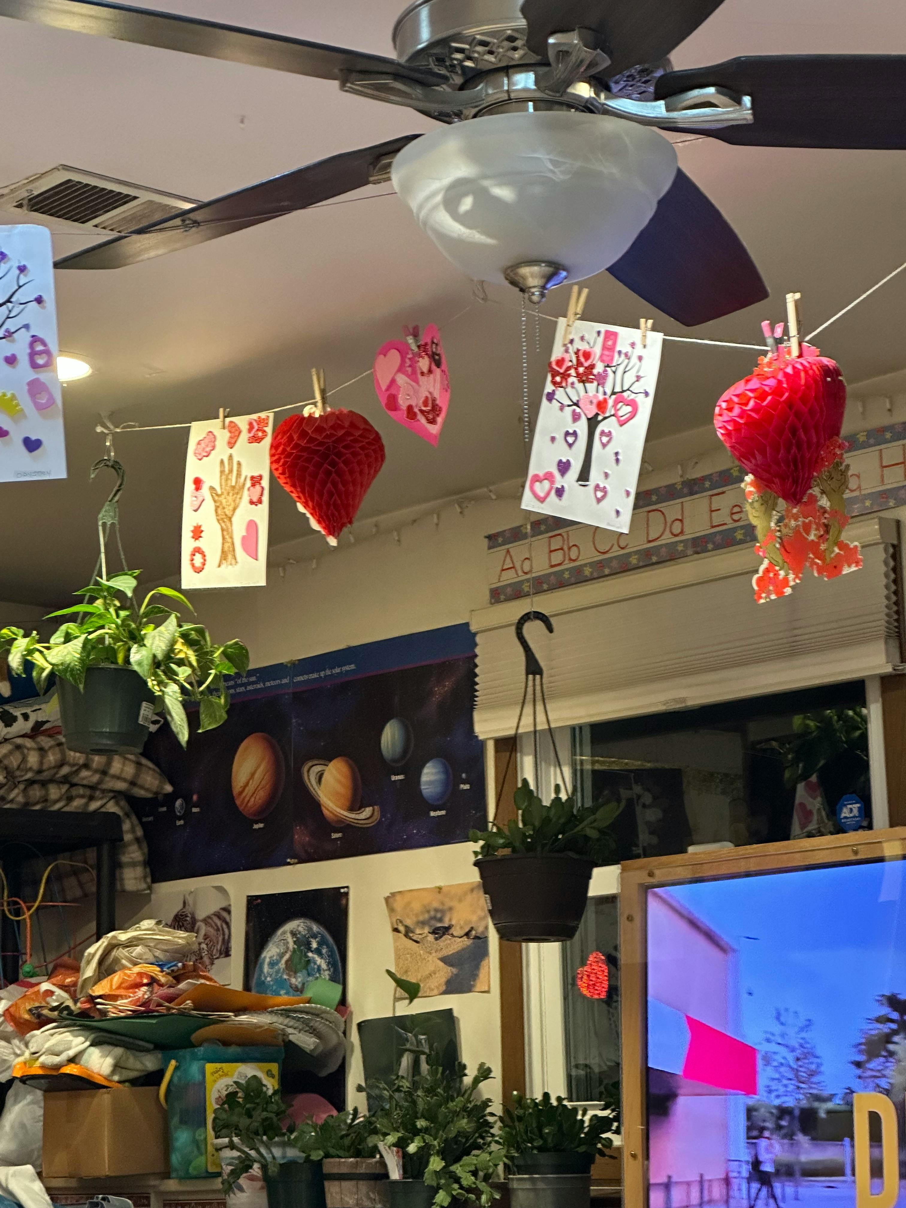 Ceiling fan with paper hearts and drawings hanging from a string