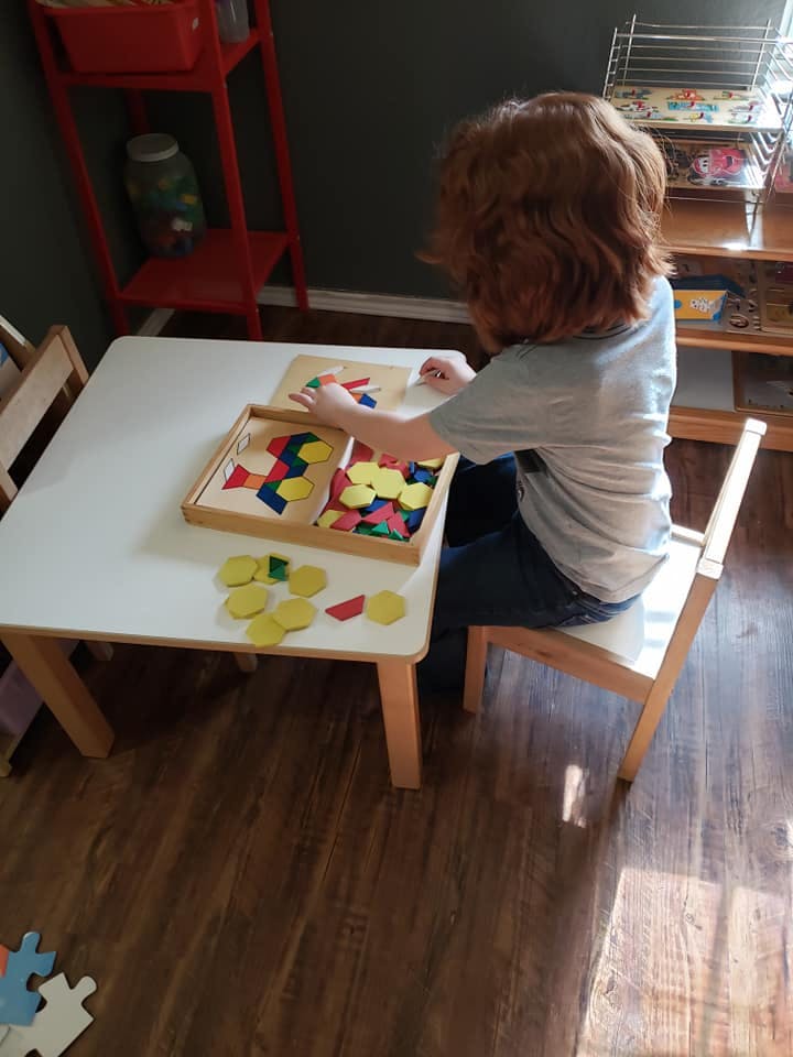 Child playing with colorful geometric shapes at a table