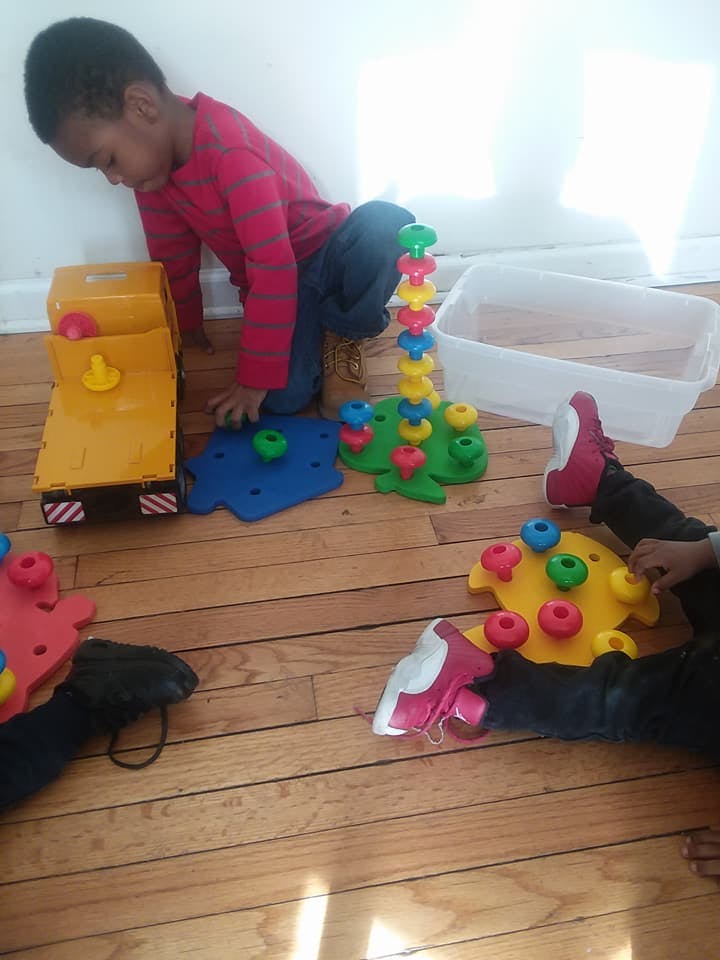 Child playing with colorful stacking toys on a wooden floor
