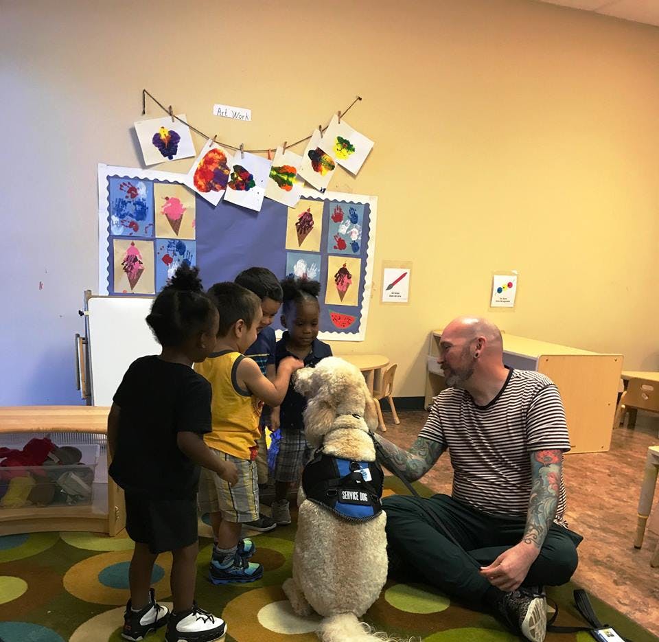 Adult and children interacting with a dog in a classroom