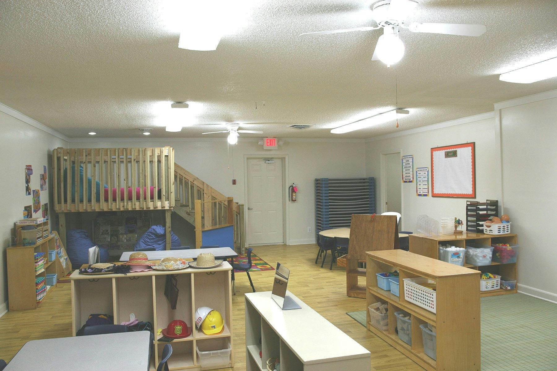 Empty classroom with wooden play structure and various shelves