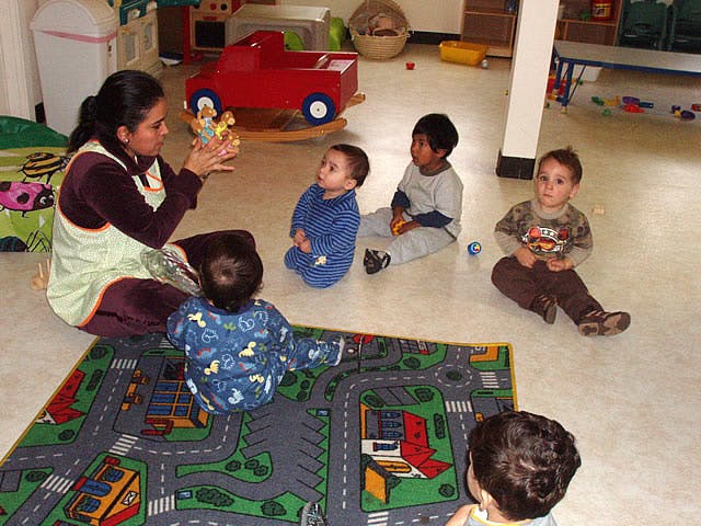 Person sitting on floor with four children in a classroom