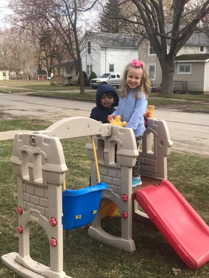 Two children playing on a small outdoor playset