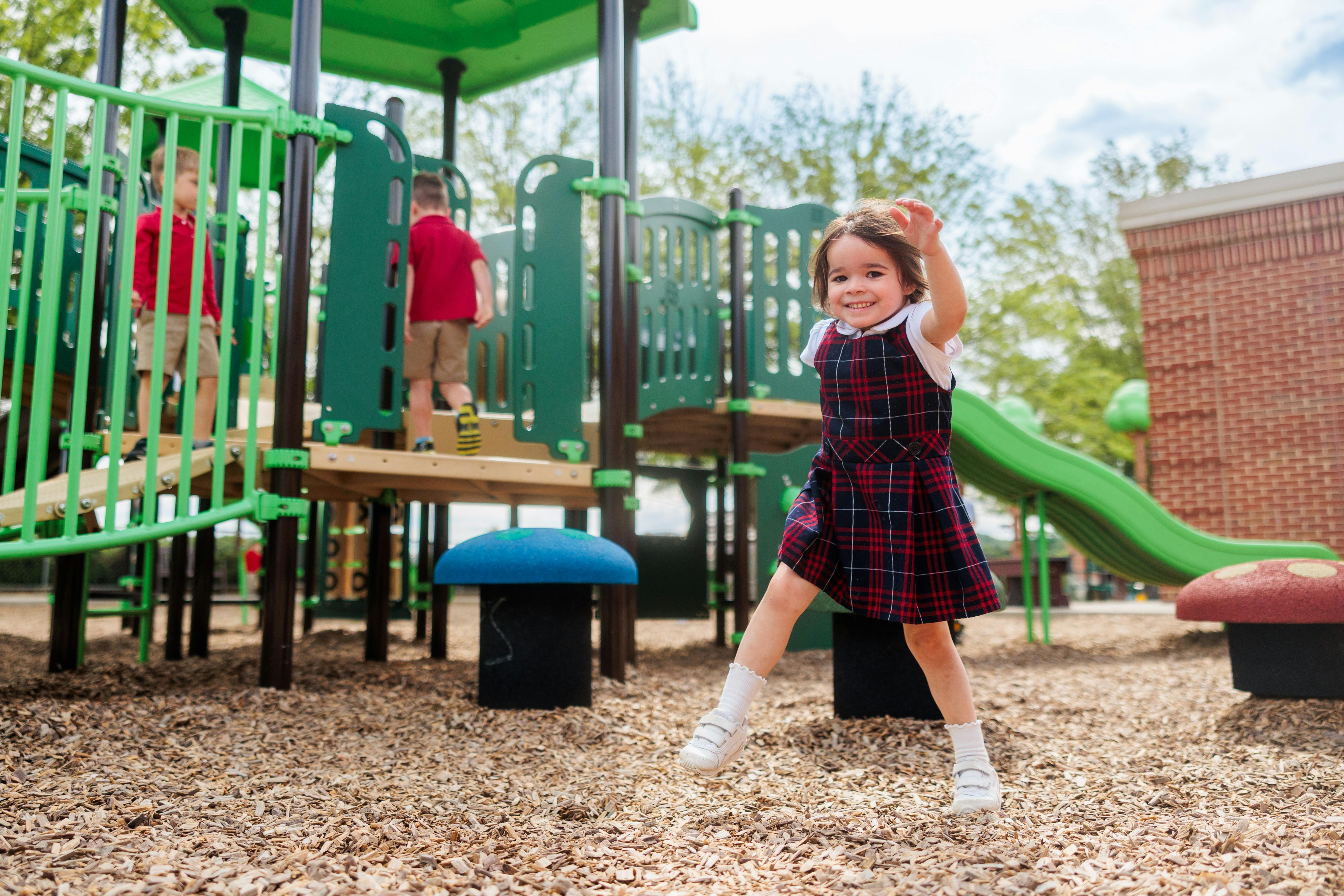 Child jumping on a playground with other children in the background