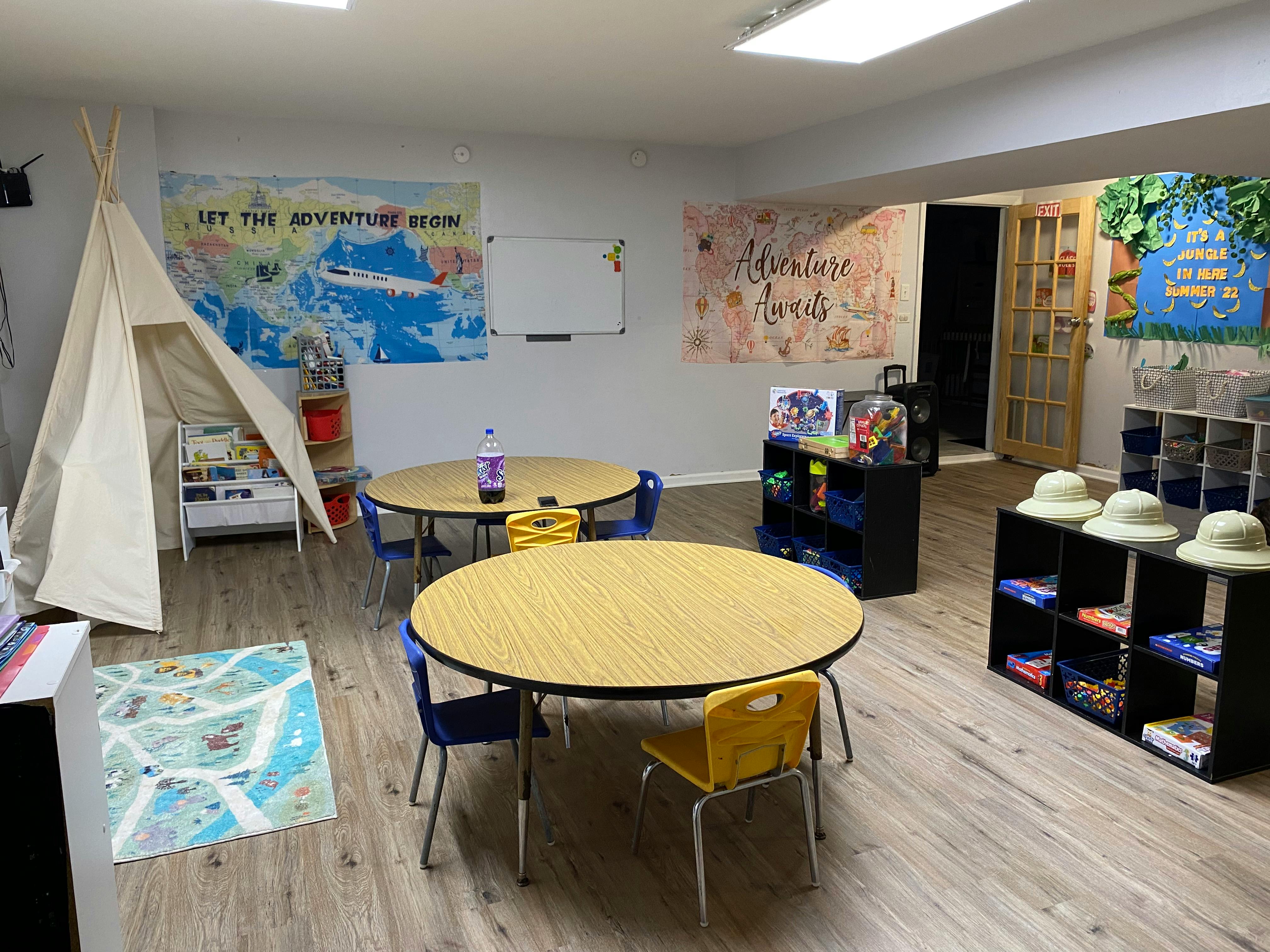 Classroom with small tables and chairs, a teepee, and wall decorations