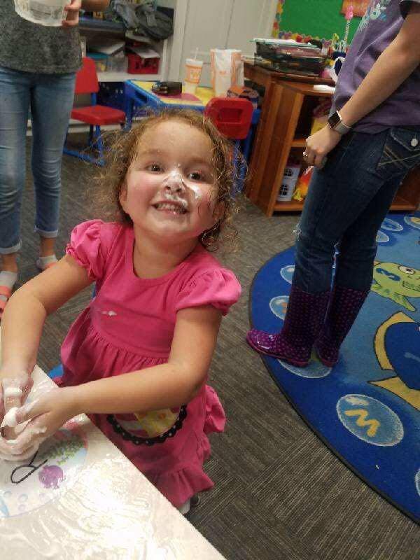 Child with flour on face and hands at a table