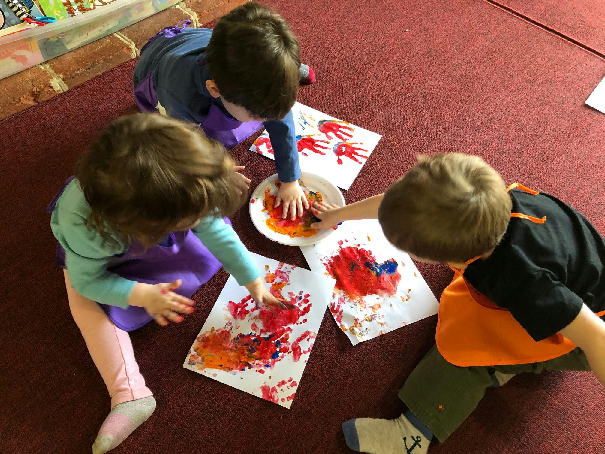 Three children finger painting on paper
