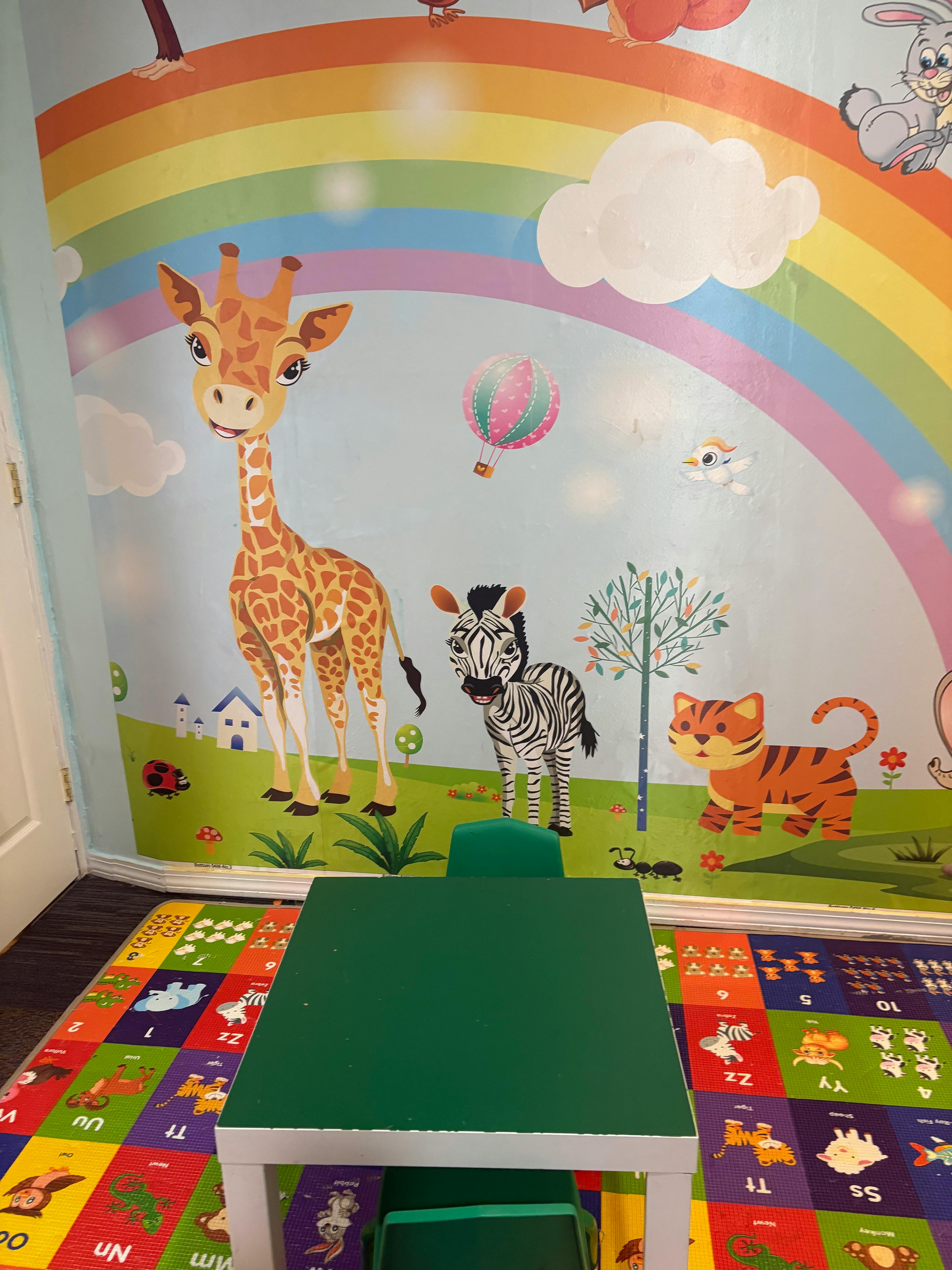 Giraffe, zebra, and tiger cartoon animals on a wall with a rainbow