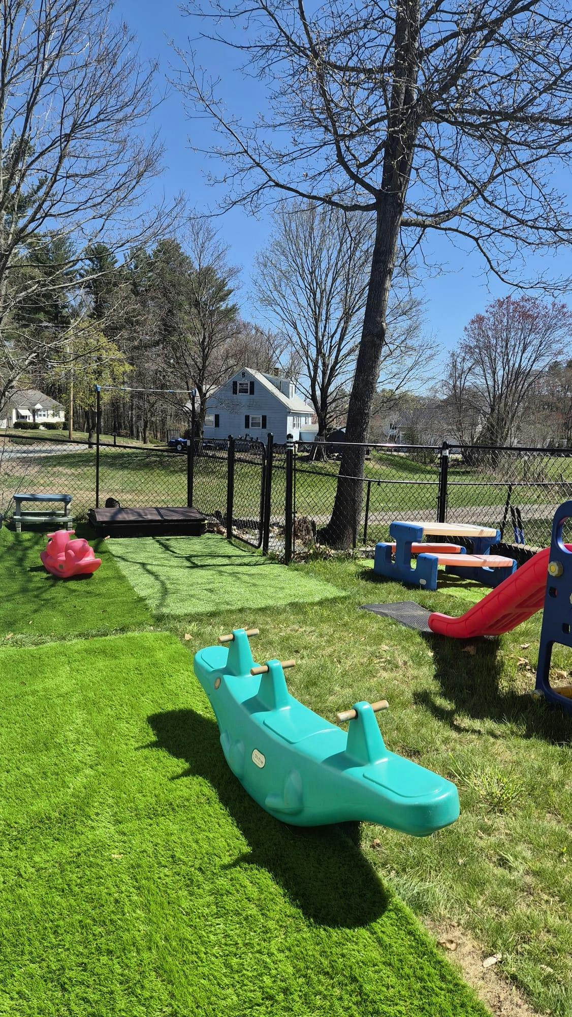 Playground area with plastic animal spring rider, picnic table, and slide