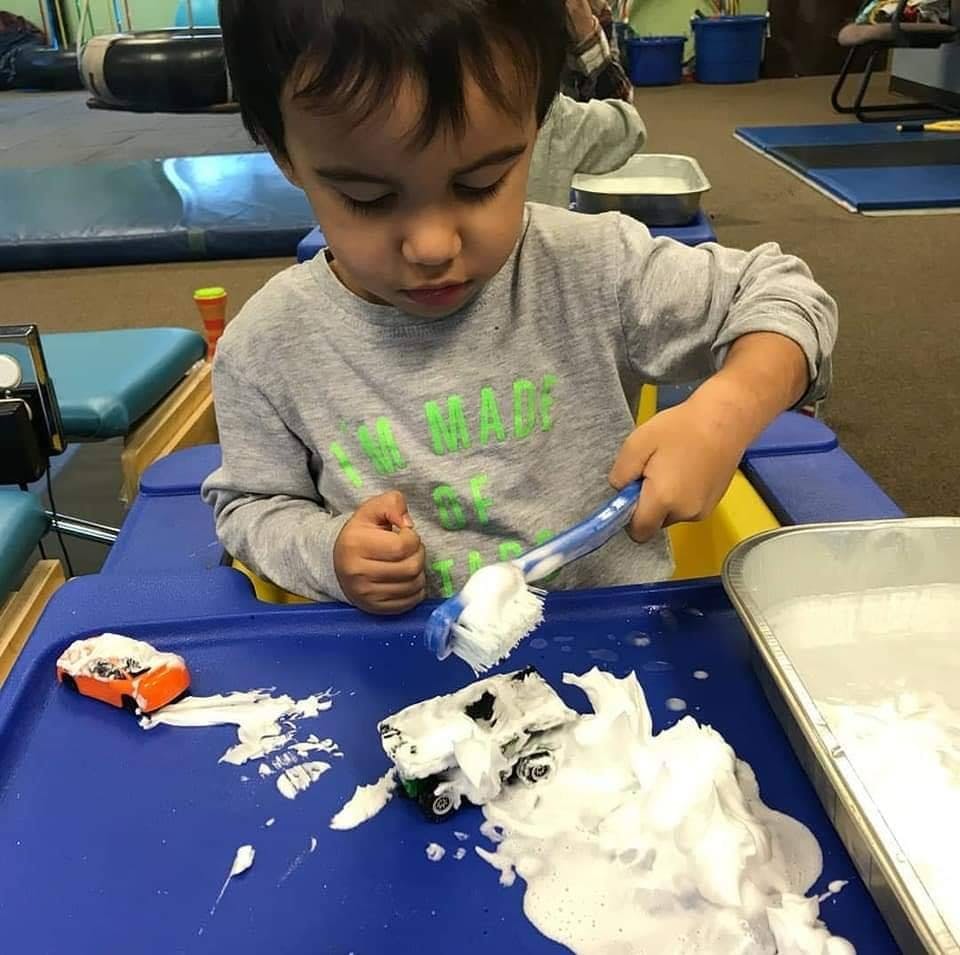 Child playing with toy cars and shaving cream