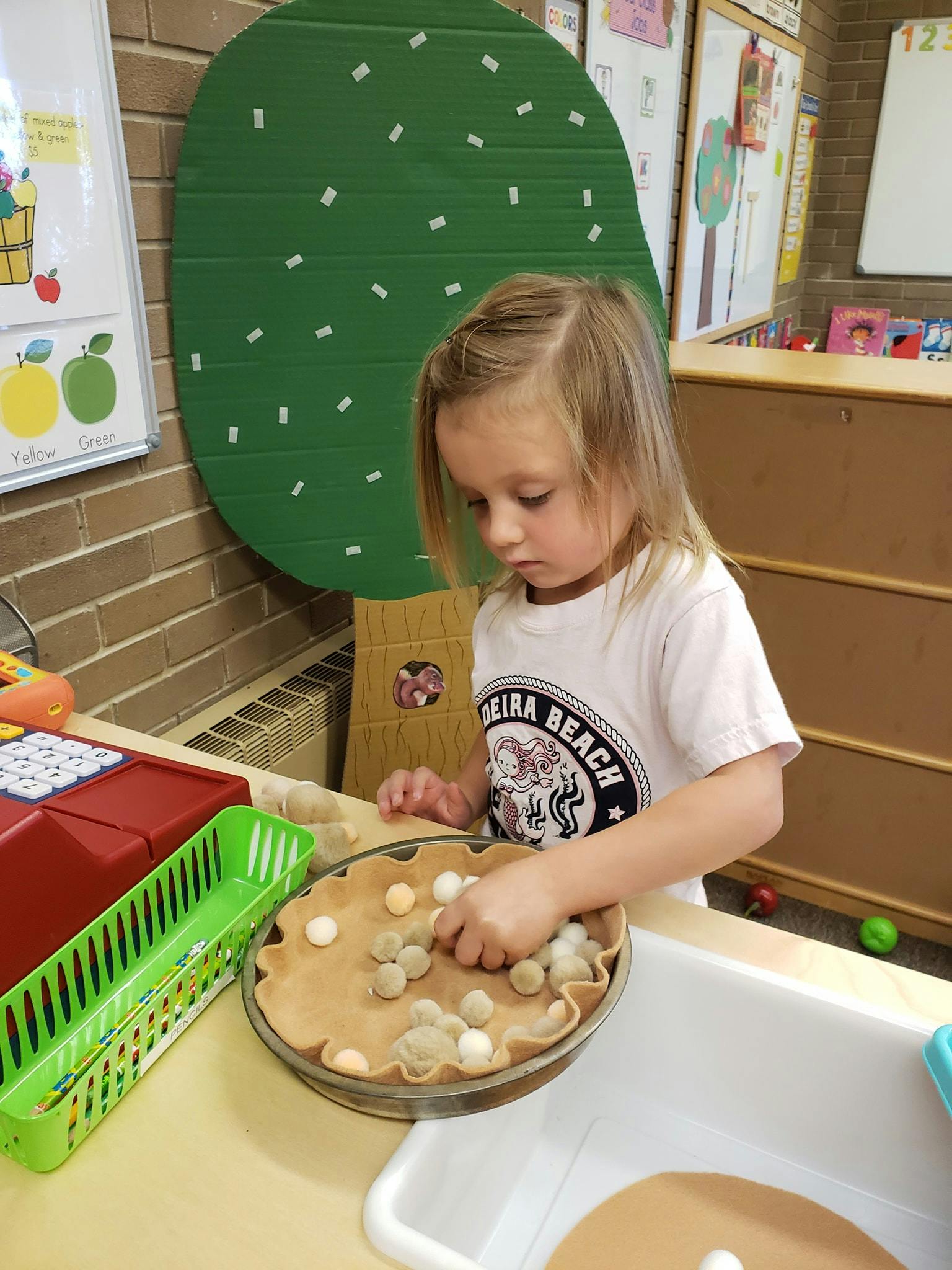 Child playing with a toy pie and small pom-poms