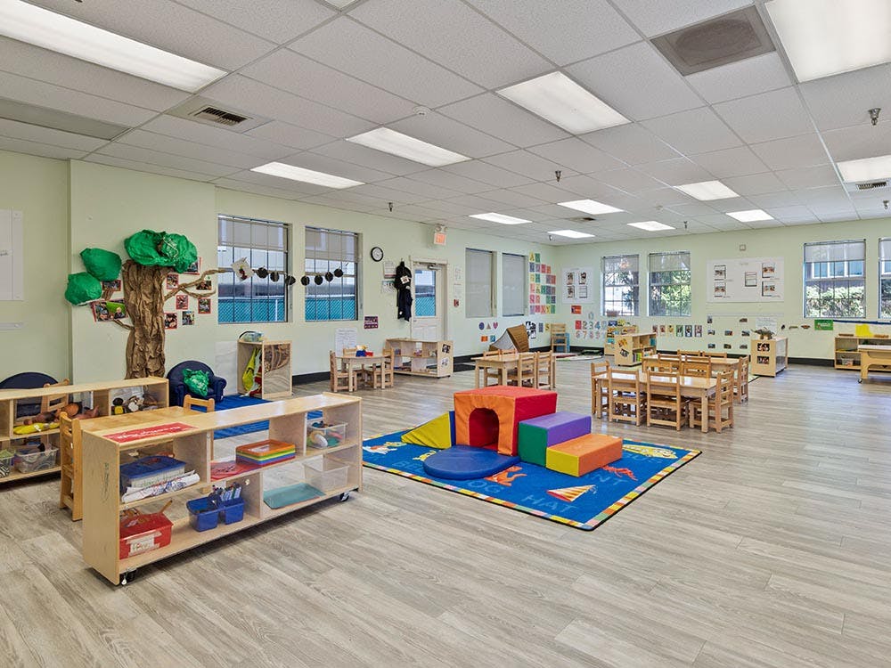 Classroom with play areas, small tables and chairs, and a tree decoration