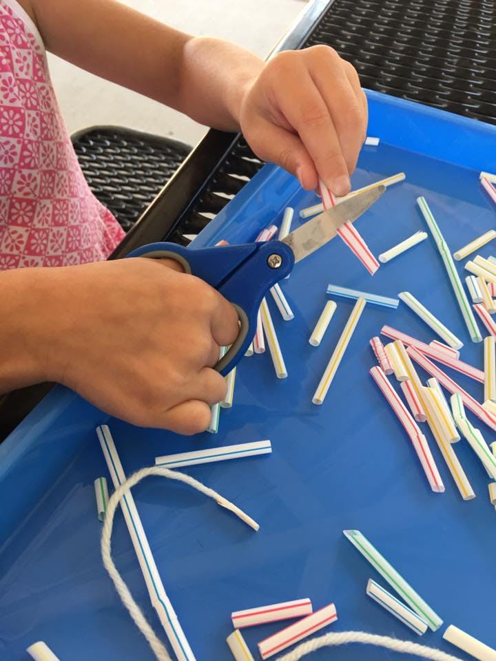 Person cutting plastic straws with scissors