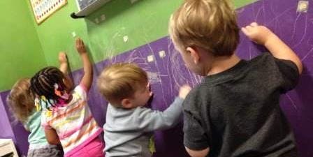 Children drawing on a purple wall