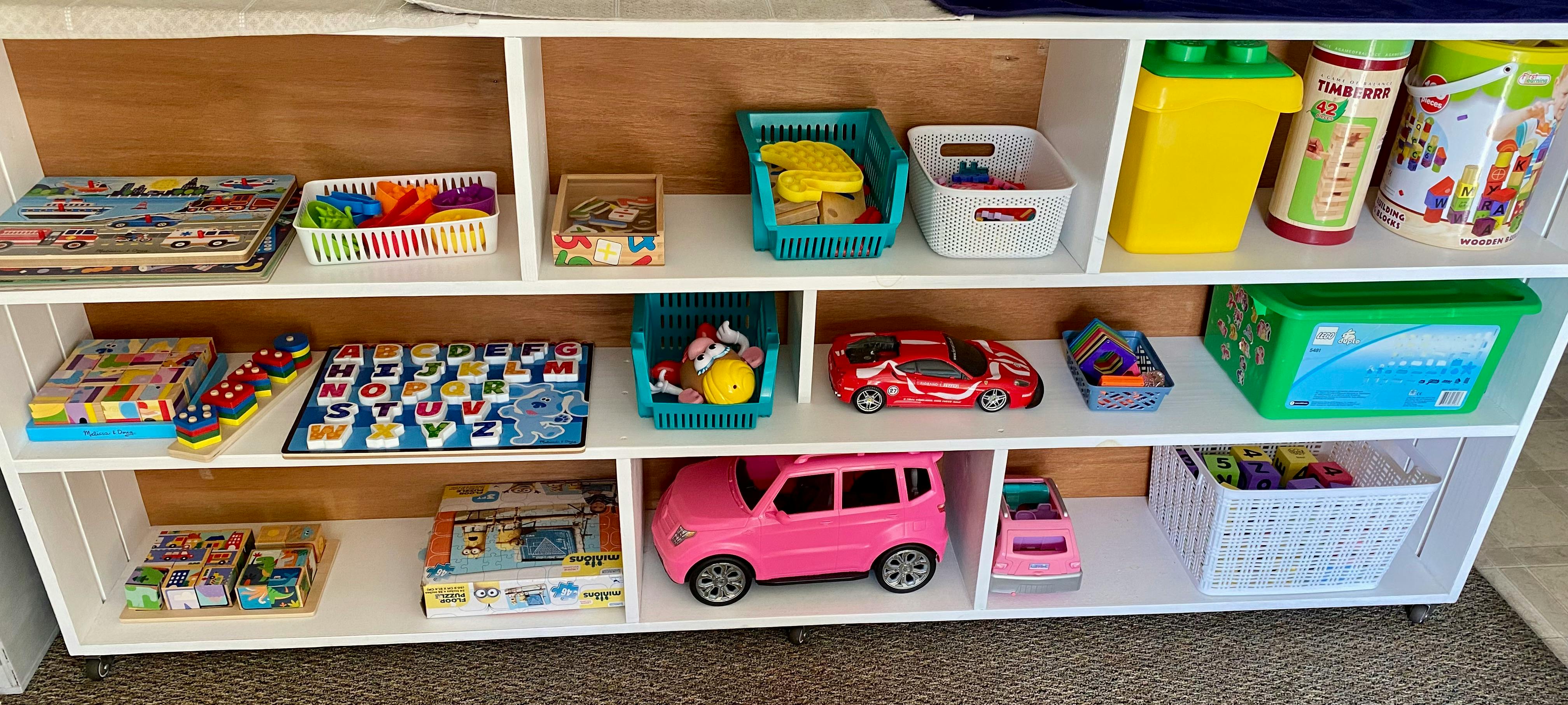 White shelf unit filled with a variety of colorful children's toys and puzzles