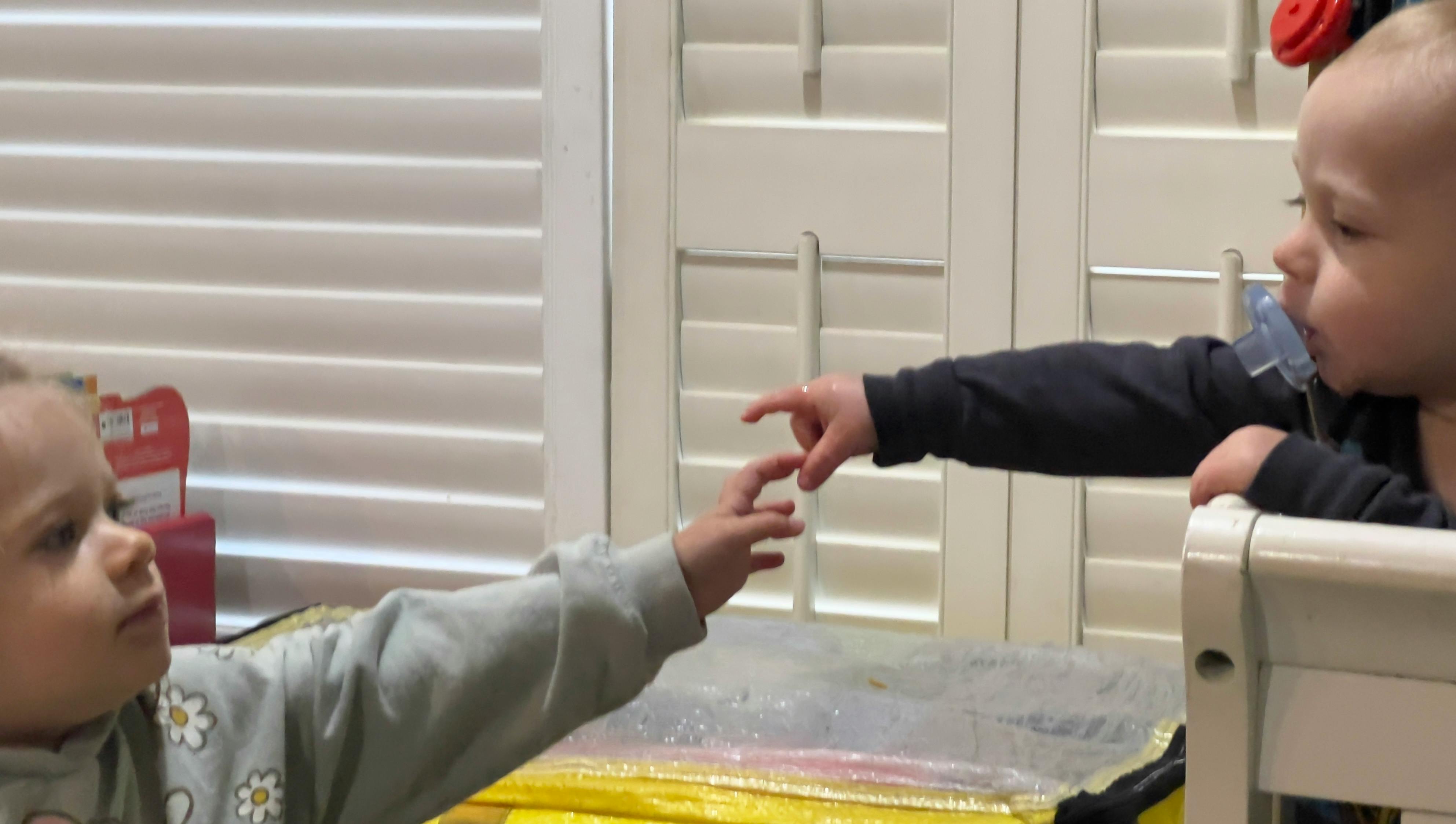Two children reaching out to touch each other's fingers