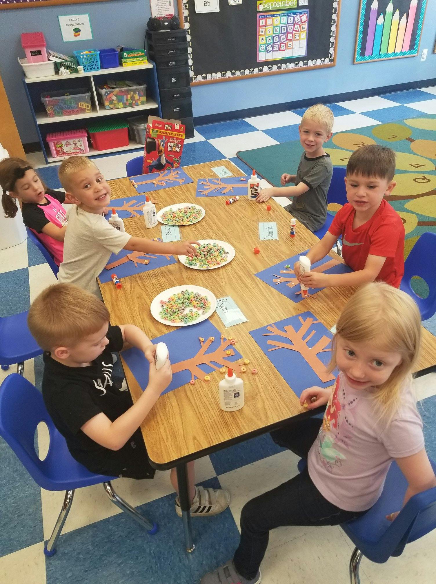Children doing crafts at a table in a classroom