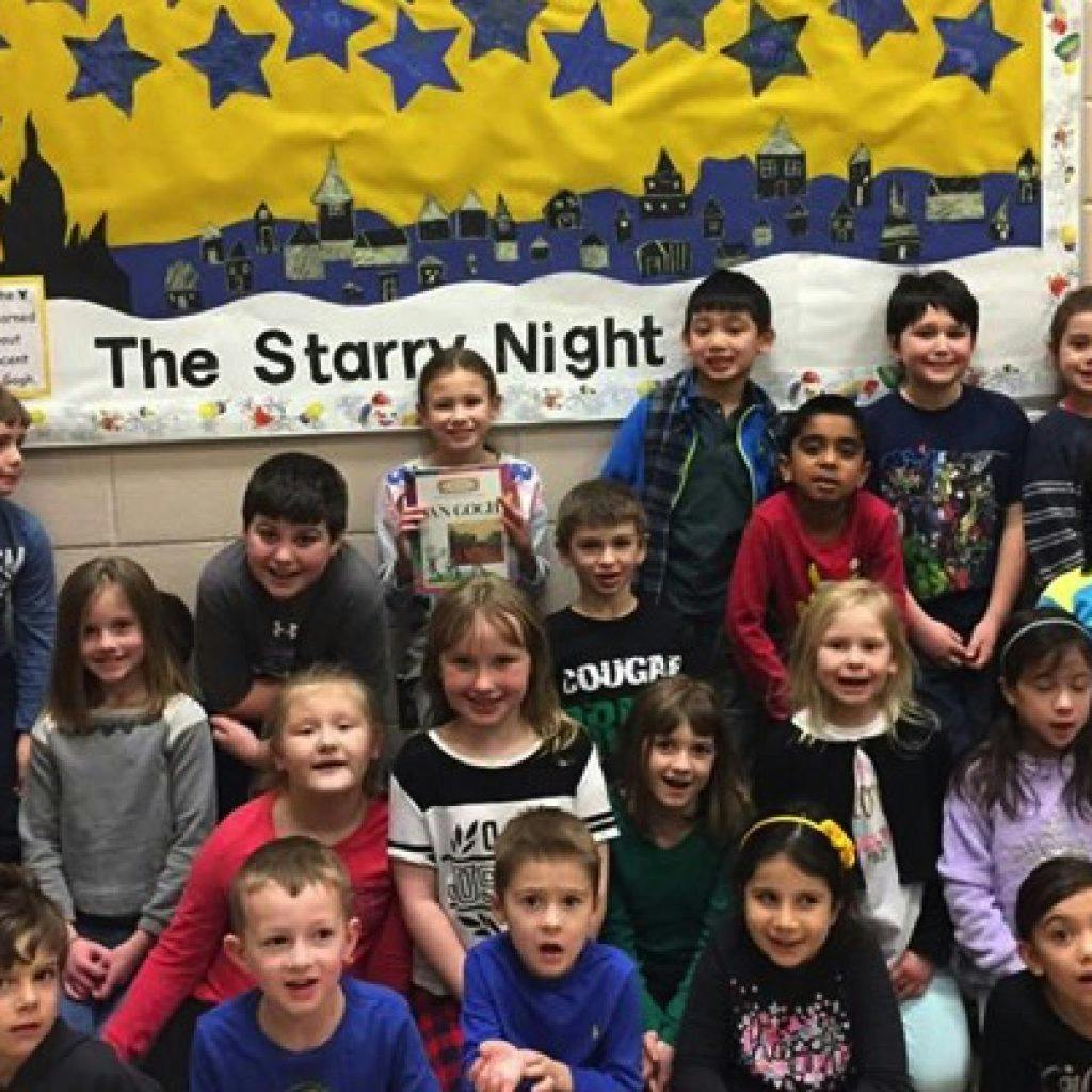 Group of children posing in front of a banner that reads "The Starry Night"