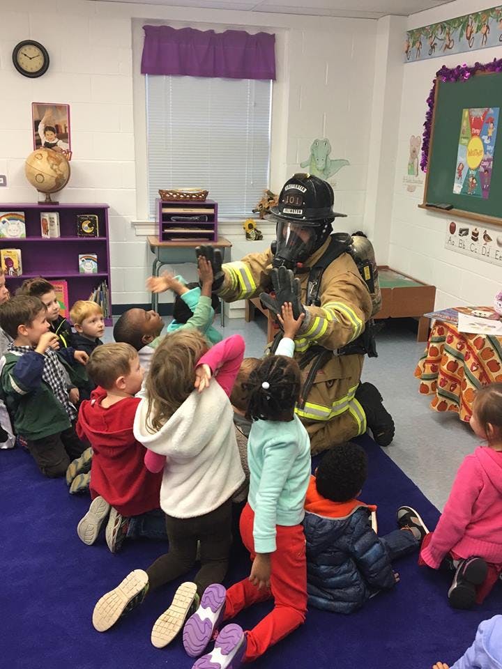 Firefighter in full gear interacting with children in a classroom