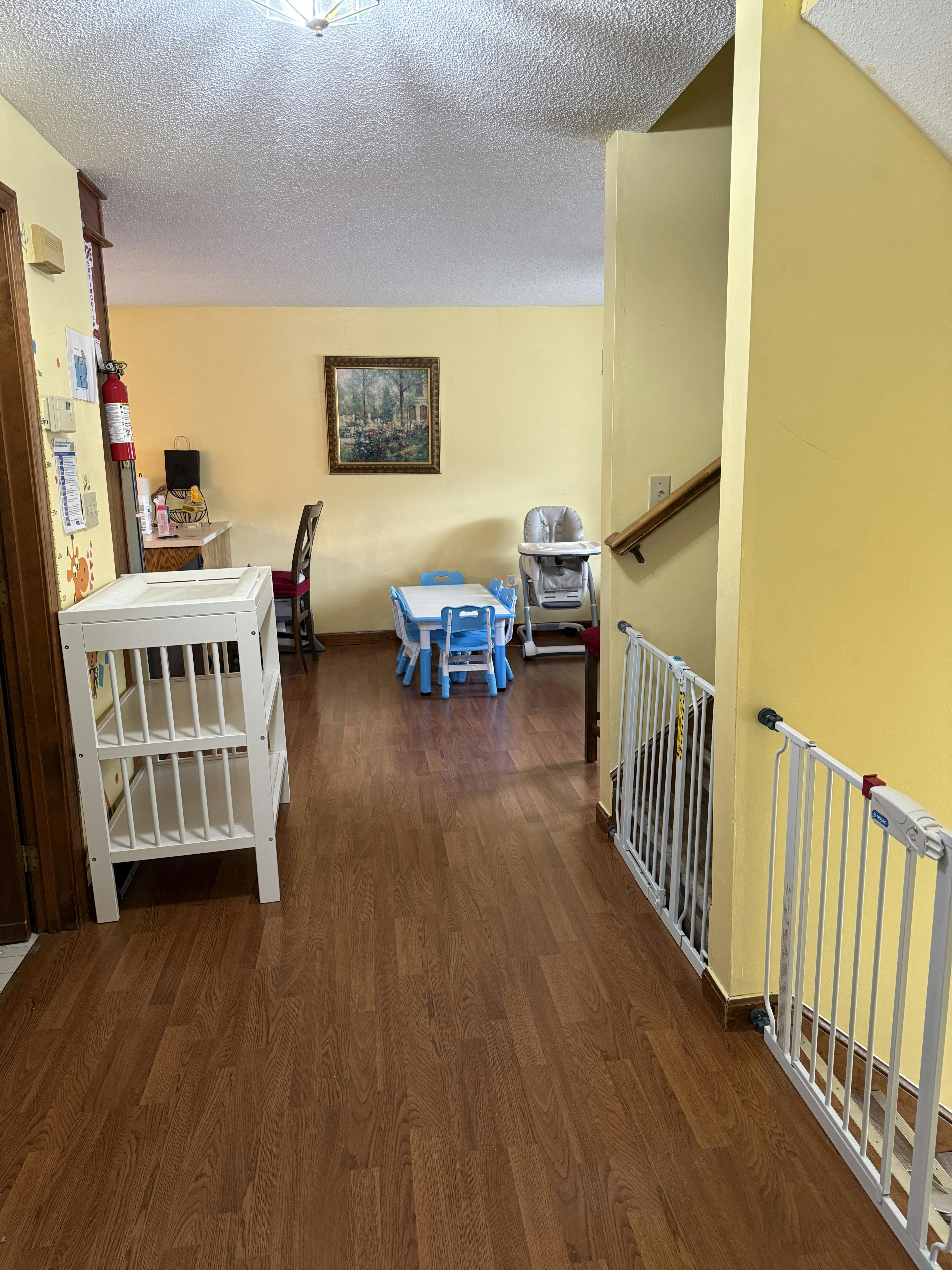 Hallway with a changing table, small table and chairs, and baby gates