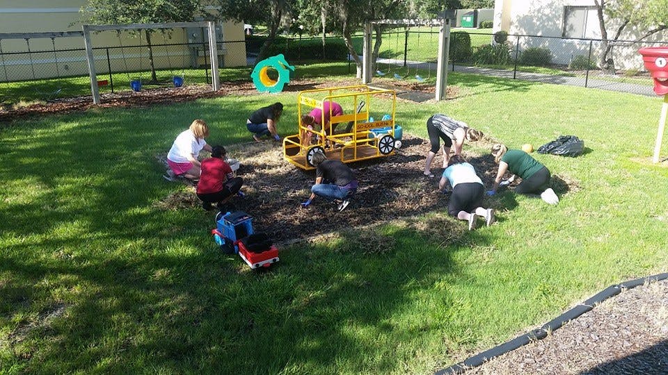People and children digging in dirt on a playground
