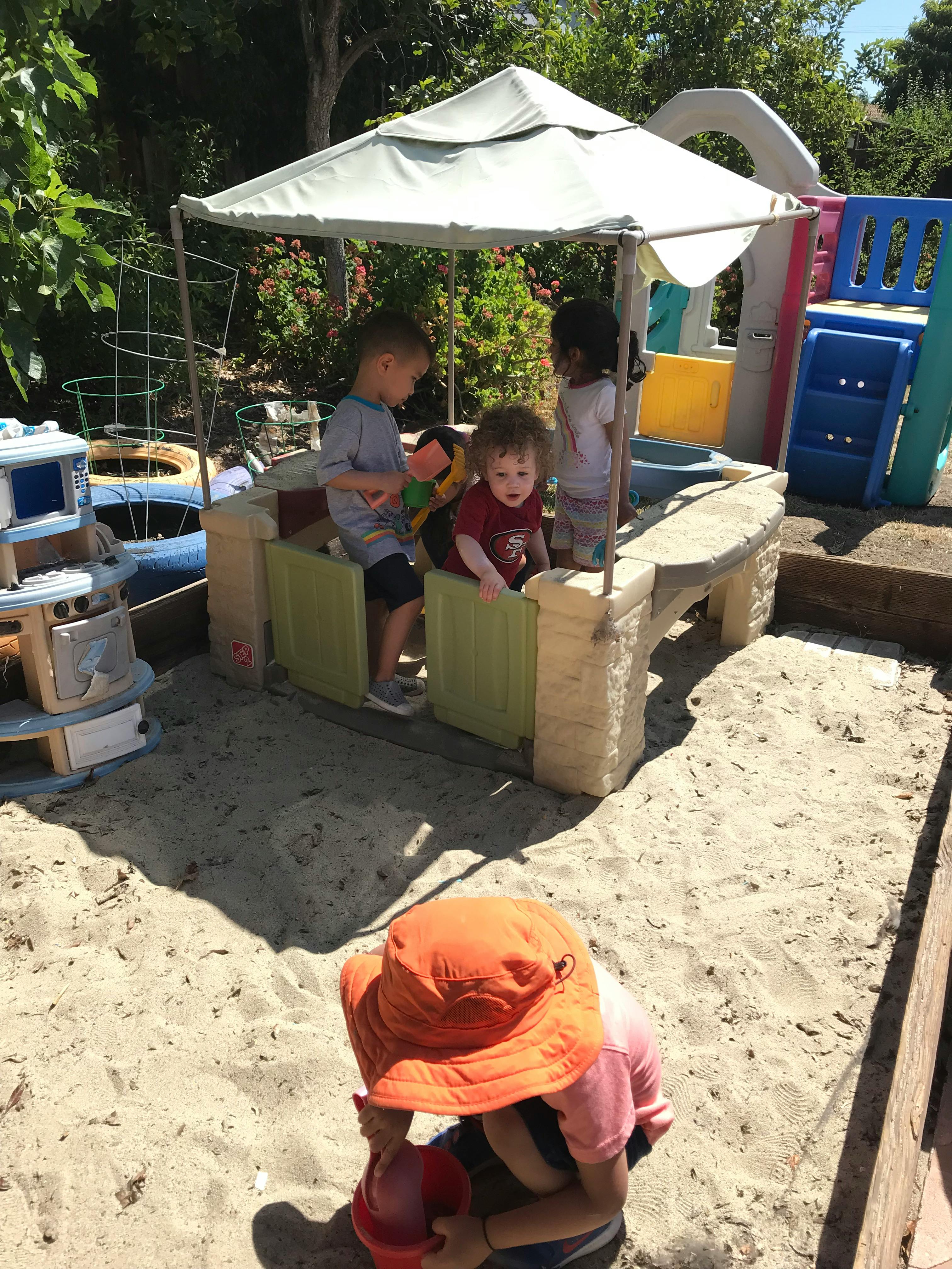 Children playing in a sandbox with a small umbrella