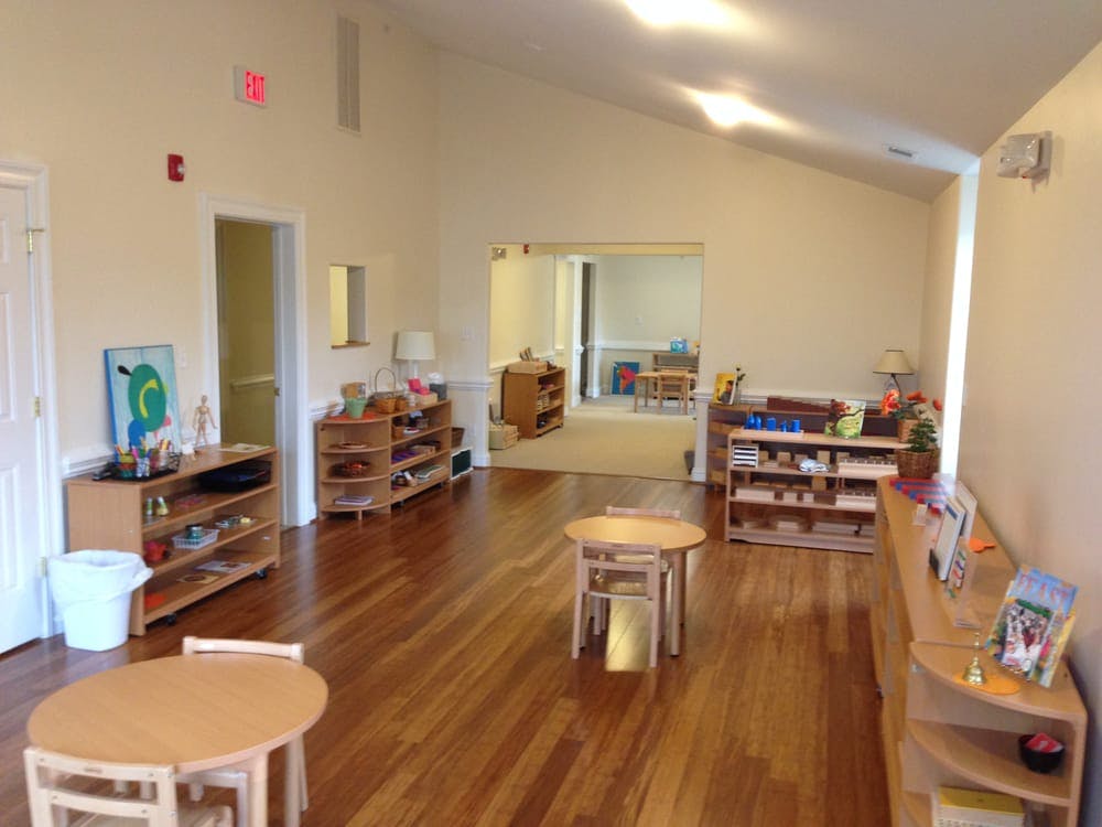 Empty classroom with small wooden tables and shelves