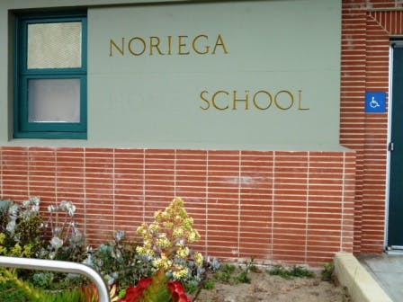 Noriega School sign on a building with a window and a door