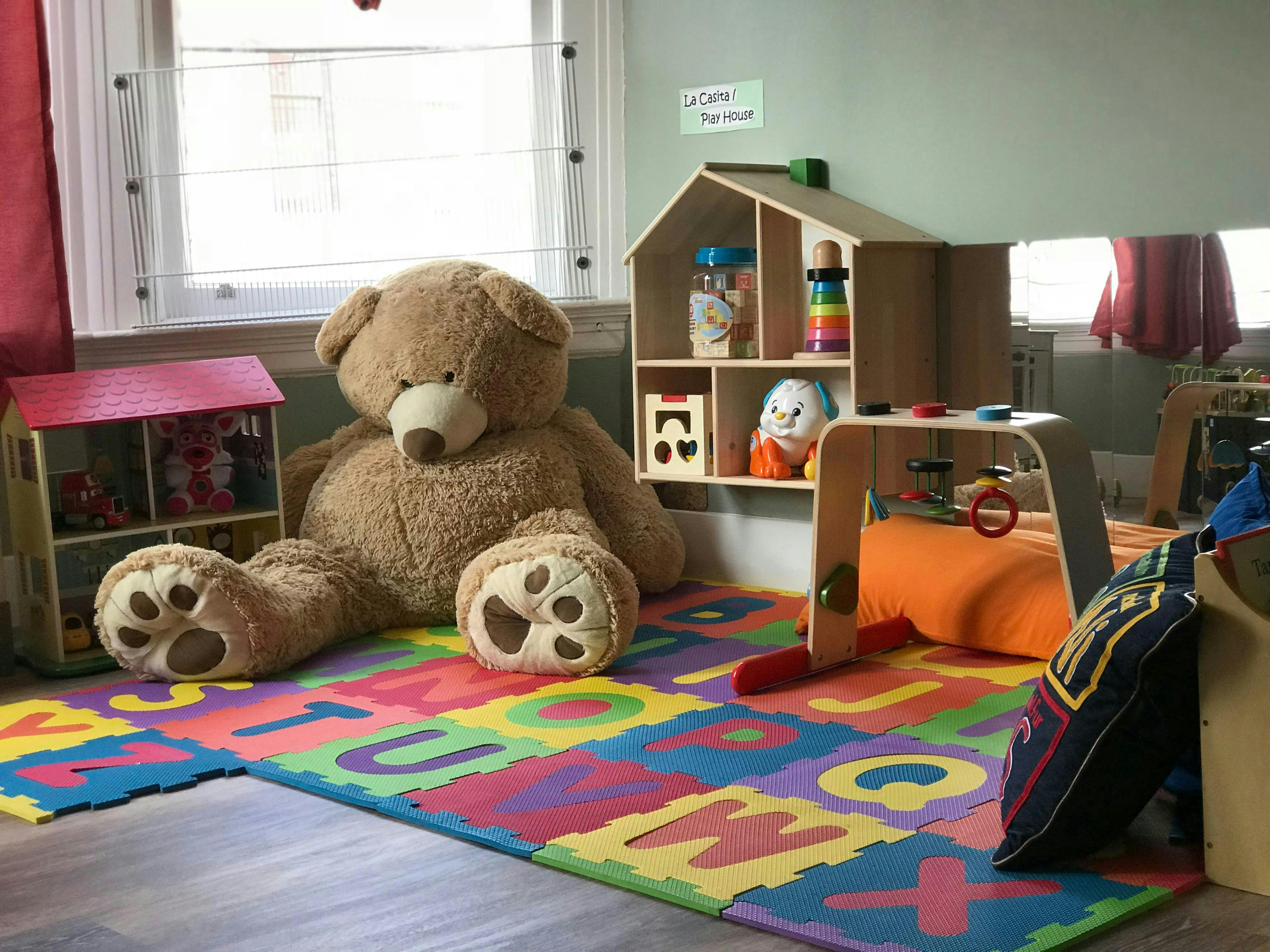 Large teddy bear and toys on a colorful alphabet play mat