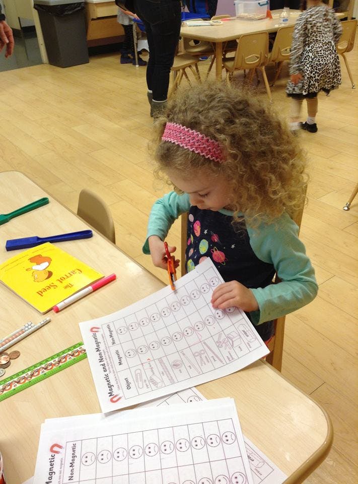 Child cutting paper with scissors at a table
