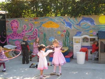 Children playing outdoors near a wall mural