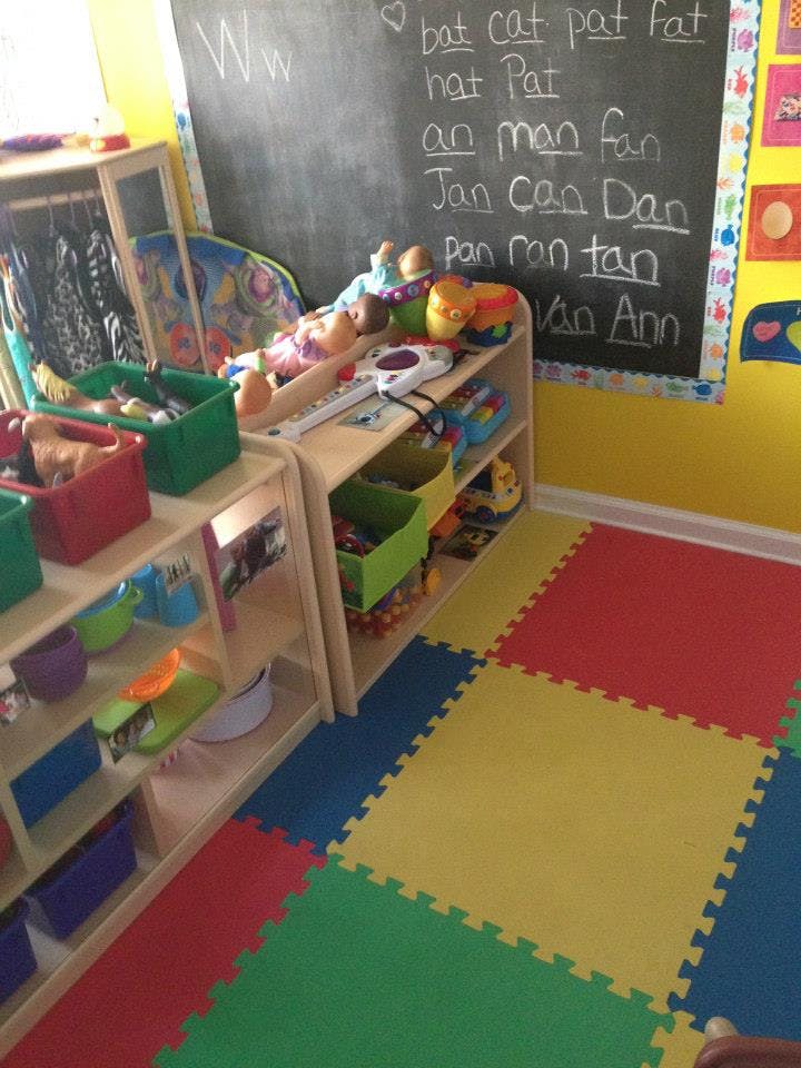 Classroom with a chalkboard, shelves of toys, and colorful floor mats
