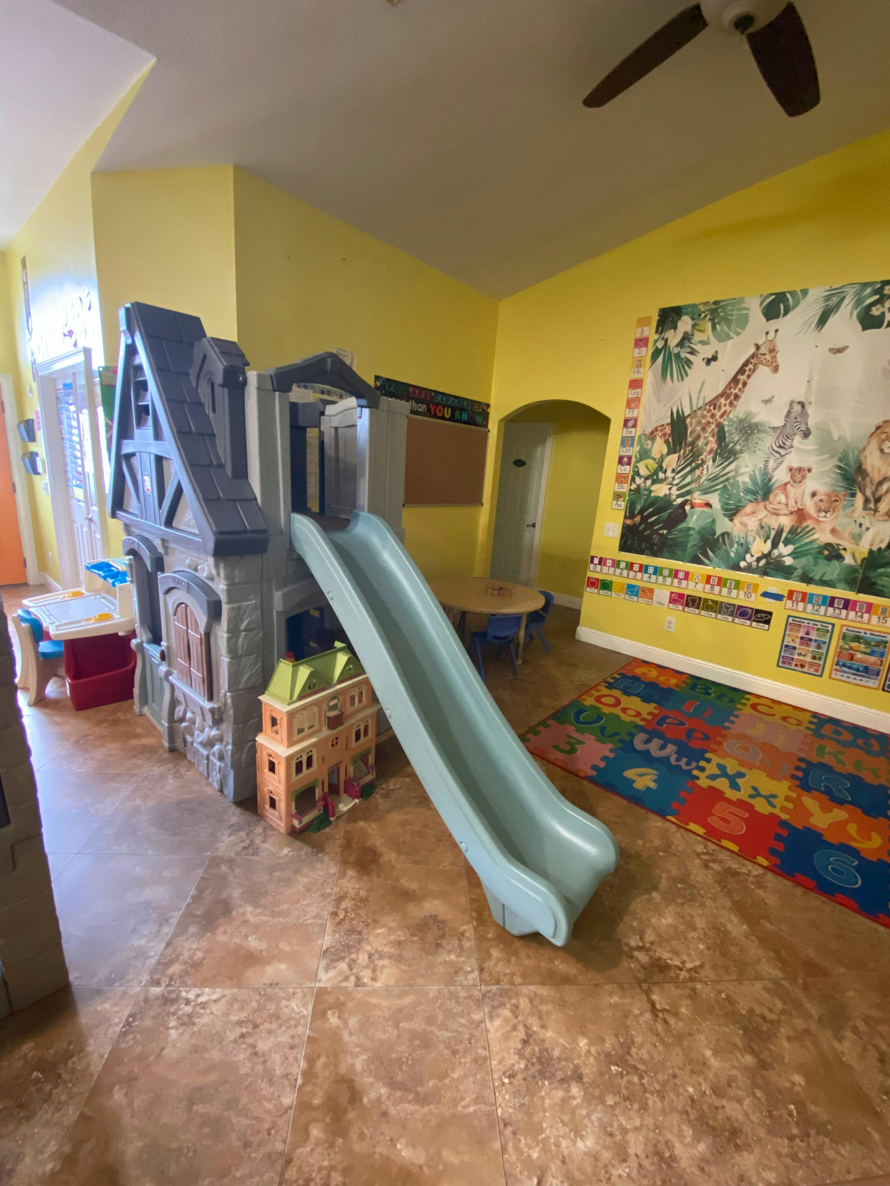 indoor playhouse with slide and colorful alphabet mat in a play area