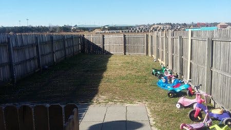 Backyard with a wooden fence and several children's ride-on toys