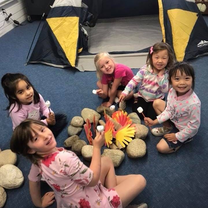 Children sitting around a pretend campfire with marshmallows on sticks