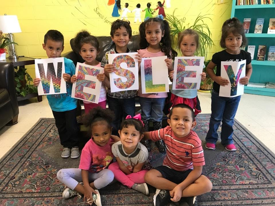 Group of children holding up letters spelling "WESLEY"