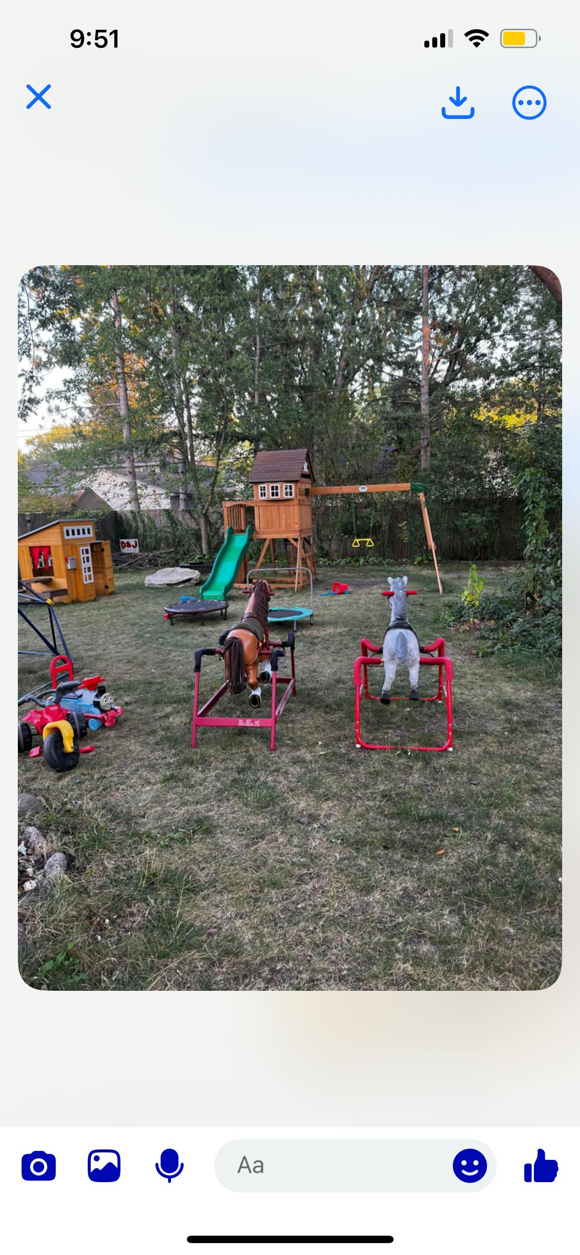 Backyard playground with a wooden playset, slide, and spring riders