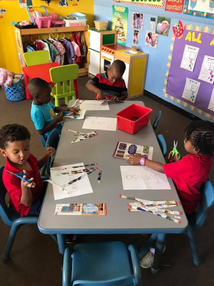 Four children sitting at a table doing crafts in-class activities