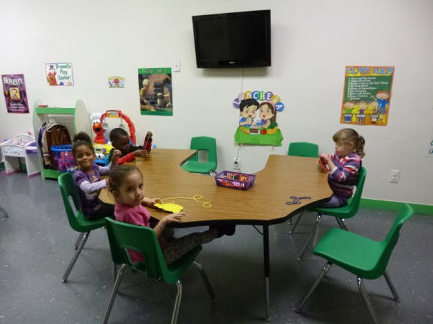 Four children sitting at a table in a classroom