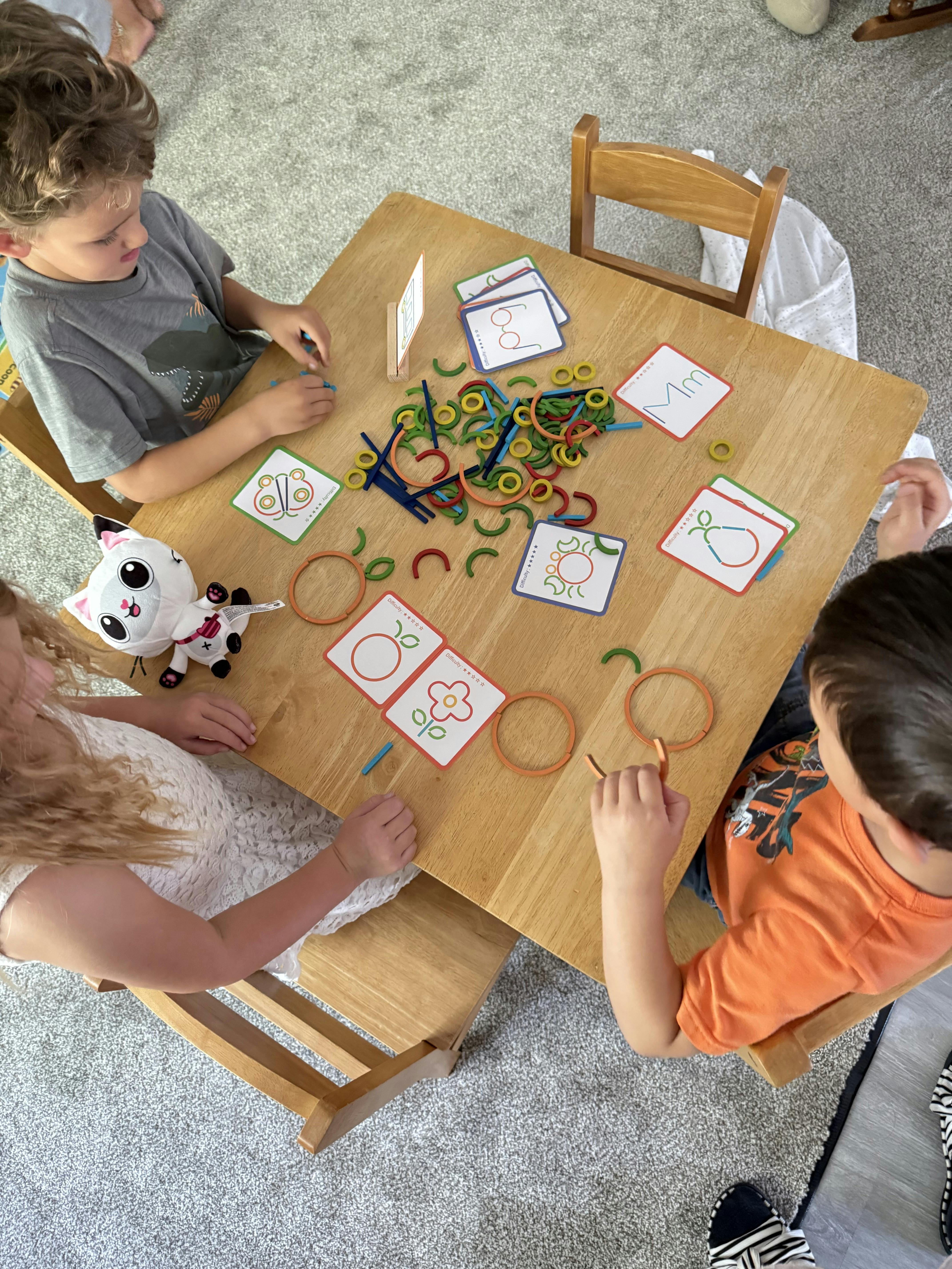 Children sitting at a table playing with colorful pattern blocks and cards