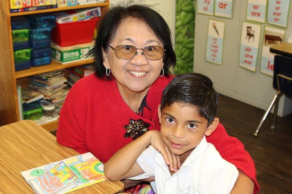 Adult and child sitting at a desk in a classroom
