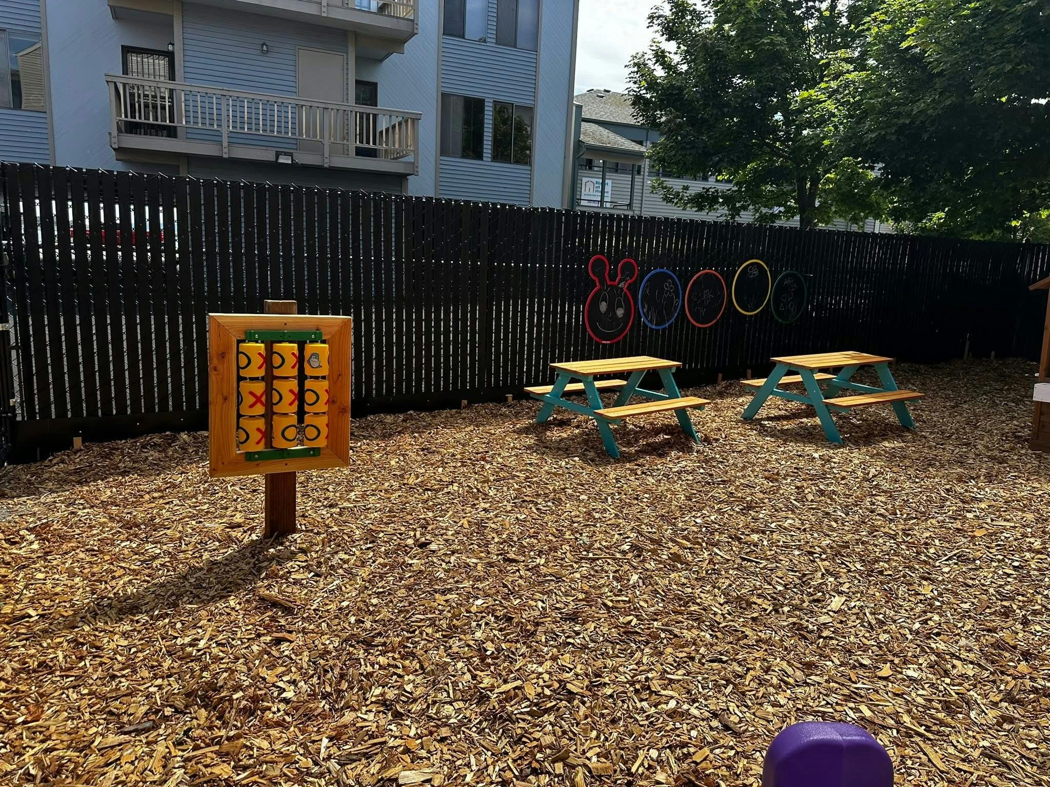 Outdoor play area with tic-tac-toe game and two picnic tables