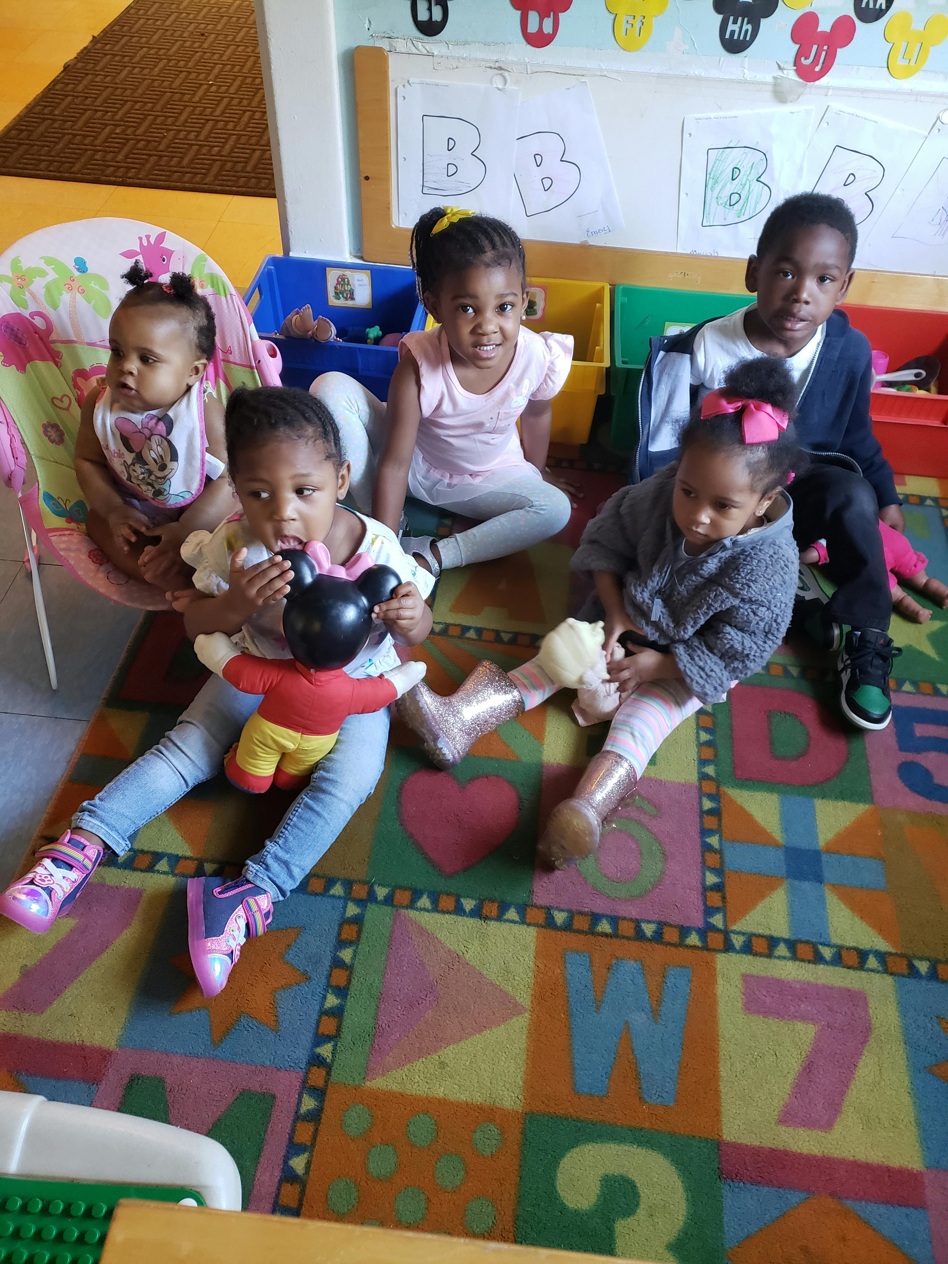 Children playing with toys on a colorful alphabet rug